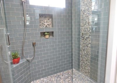 Textured Pebble Tile Floor Paired with Soft Blue Subway Tile Walls | Tiles Gone Wild